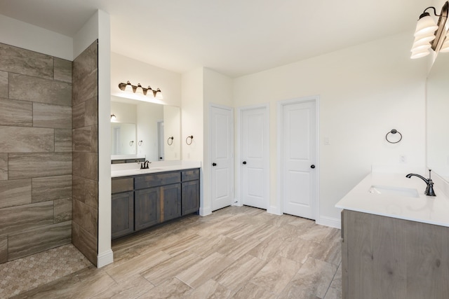 full bathroom featuring a sink, baseboards, and two vanities