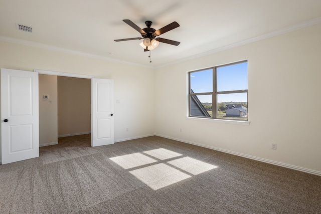 empty room with visible vents, baseboards, a ceiling fan, ornamental molding, and carpet floors