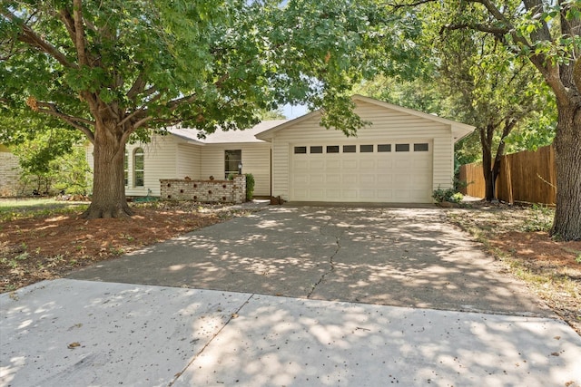 view of front facade with an attached garage, driveway, and fence