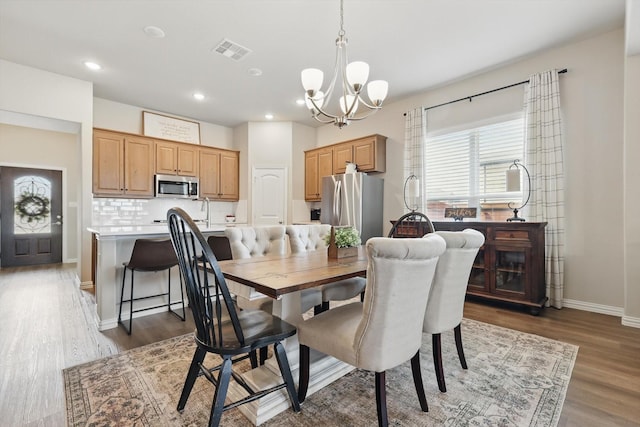 dining room with baseboards, visible vents, wood finished floors, a chandelier, and recessed lighting