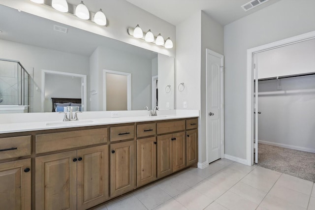 full bath featuring double vanity, a shower stall, visible vents, and a sink