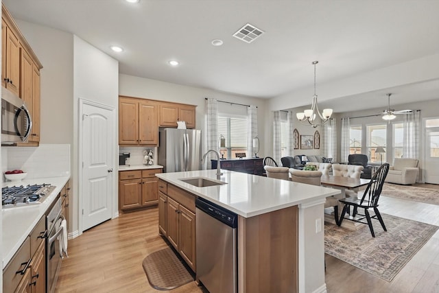 kitchen featuring light wood finished floors, visible vents, appliances with stainless steel finishes, open floor plan, and a sink