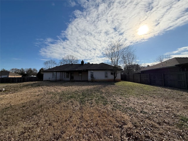 rear view of property with a lawn and a fenced backyard