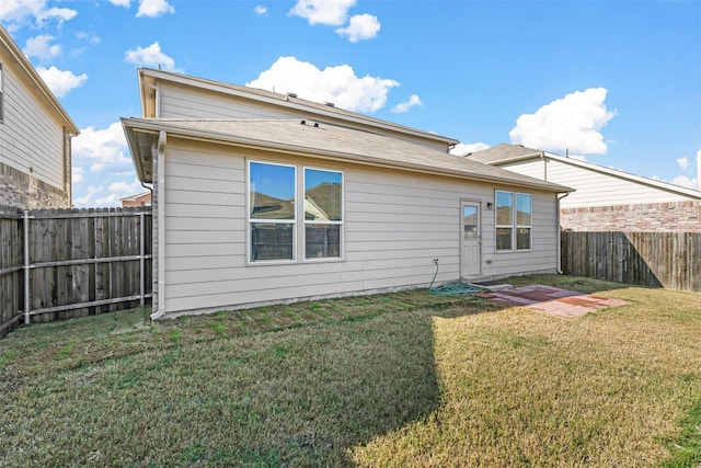 back of house with a yard and a fenced backyard