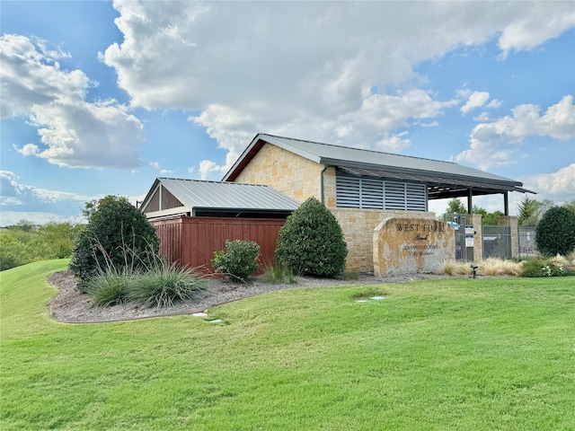 view of side of property featuring metal roof, stone siding, and a lawn