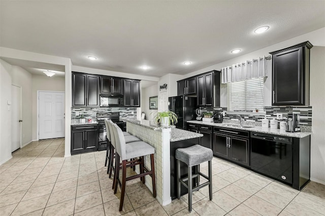 kitchen featuring dark cabinetry, a sink, black appliances, and light tile patterned floors