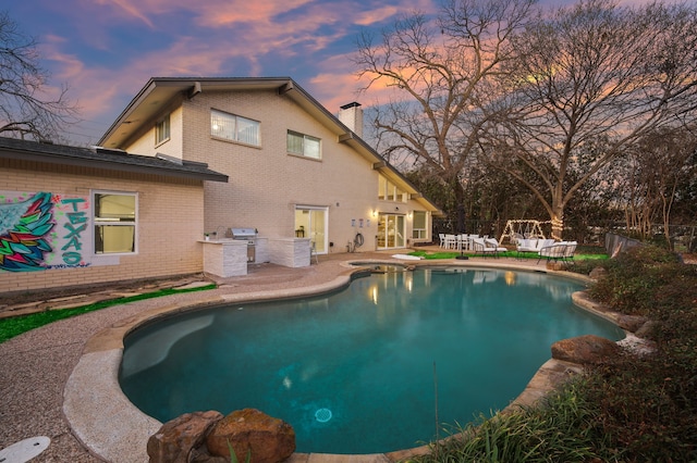 pool at dusk with a fenced in pool, area for grilling, a grill, fence, and a patio area