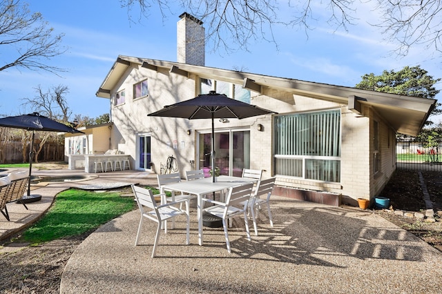 back of house featuring a patio, brick siding, fence, outdoor dining space, and a chimney