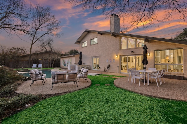 rear view of house featuring brick siding, a lawn, an outdoor pool, a chimney, and a patio area