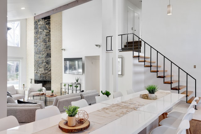 interior space with a towering ceiling, a fireplace, stairway, and wood finished floors