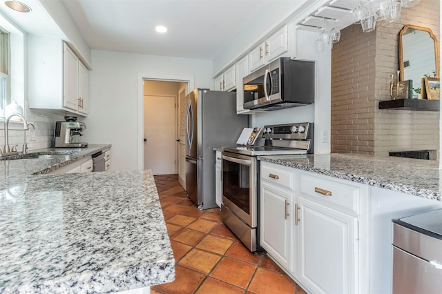 kitchen with a sink, decorative backsplash, appliances with stainless steel finishes, and white cabinetry