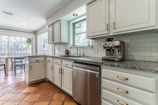 kitchen with visible vents, a sink, stone countertops, stainless steel dishwasher, and decorative backsplash