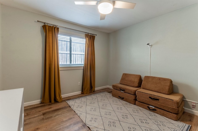 living area featuring baseboards, light wood-style floors, and a ceiling fan