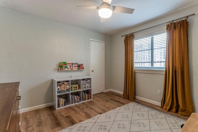 recreation room with a ceiling fan, wood finished floors, and baseboards