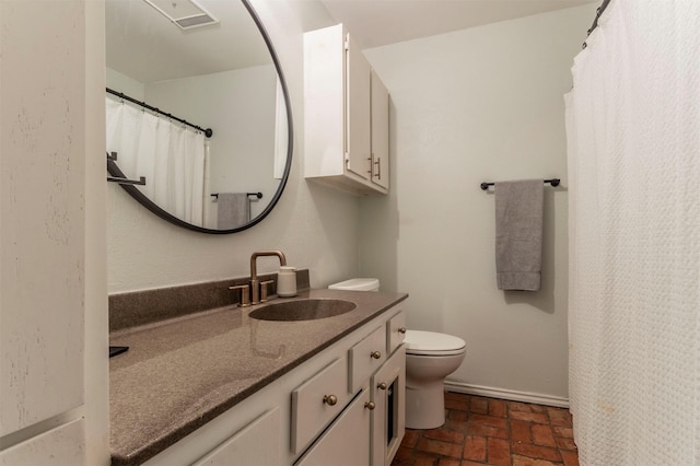 bathroom featuring vanity, toilet, baseboards, and brick floor