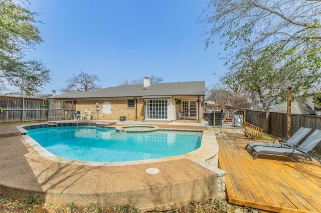 view of pool with a pool with connected hot tub, french doors, a wooden deck, and a fenced backyard