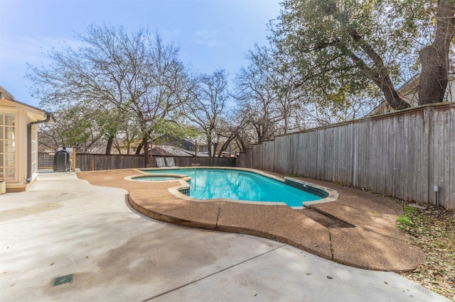 view of swimming pool with a patio area, a pool with connected hot tub, and a fenced backyard