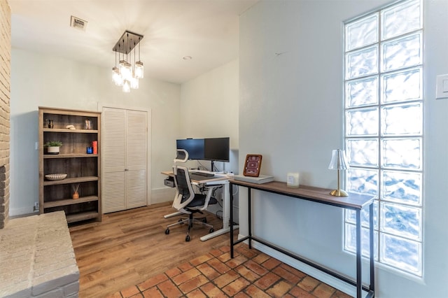 office area featuring brick floor, visible vents, baseboards, and a notable chandelier