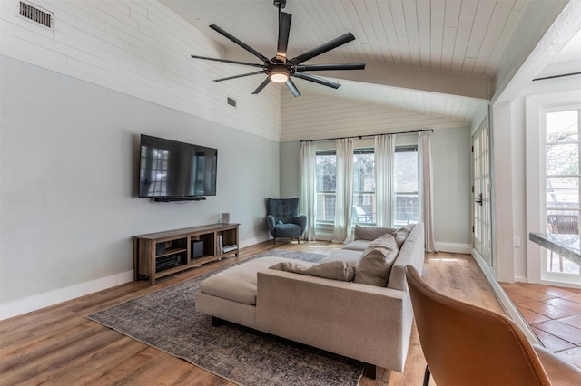 living area featuring a wealth of natural light, visible vents, lofted ceiling, and wood finished floors