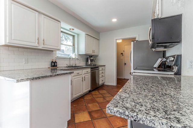 kitchen featuring a sink, backsplash, white cabinets, light stone countertops, and dishwasher