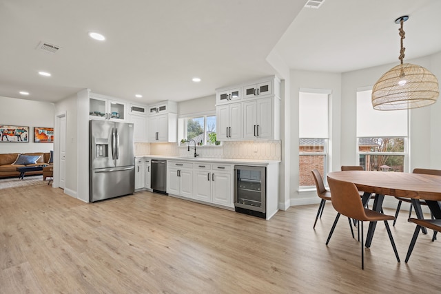 1607 Amesbury Ln, Rockwall, TX 75087 - kitchen with appliances with stainless steel finishes, wine cooler, a sink, light wood-type flooring, and backsplash