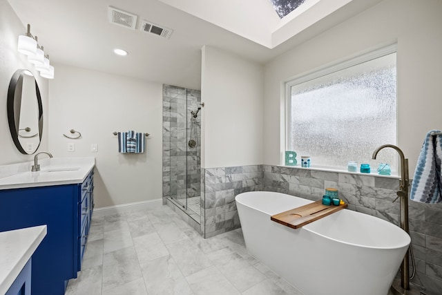 1607 Amesbury Ln, Rockwall, TX 75087 - full bath featuring vanity, marble look tiles, a shower stall, tile walls, and a freestanding tub