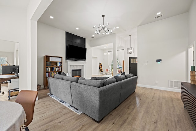 1607 Amesbury Ln, Rockwall, TX 75087 - living area with a chandelier, a high ceiling, a glass covered fireplace, light wood-type flooring, and recessed lighting