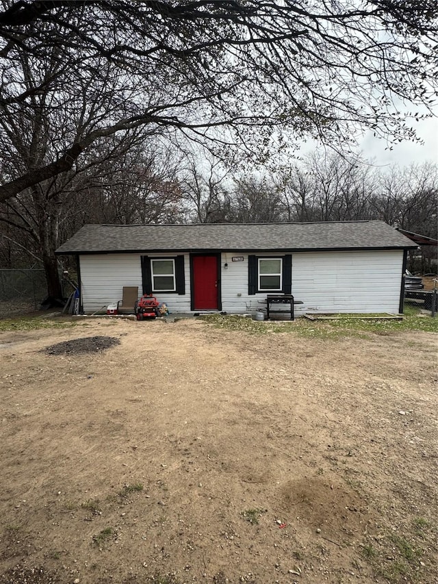 view of front of home with dirt driveway and fence