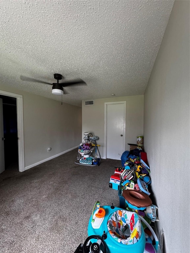 playroom featuring a textured ceiling, carpet flooring, visible vents, and baseboards