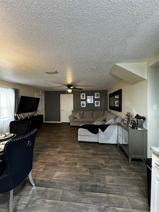 living area with a ceiling fan, a textured ceiling, and wood finished floors