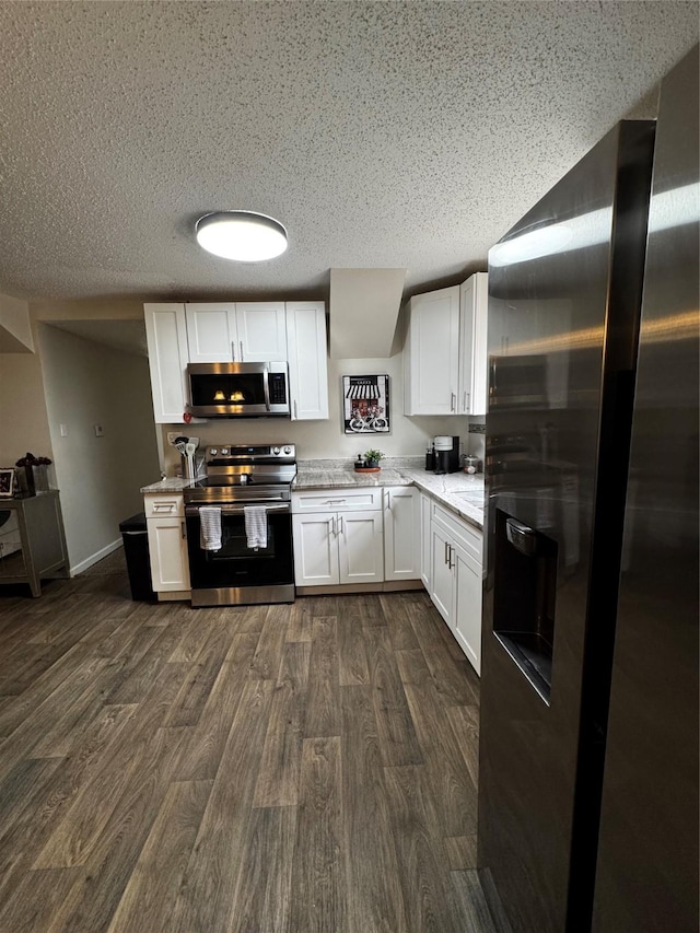 kitchen featuring white cabinets, a textured ceiling, stainless steel appliances, and dark wood-style flooring