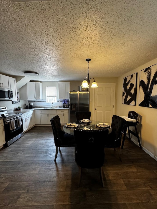 dining space with a chandelier, dark wood finished floors, a textured ceiling, and baseboards