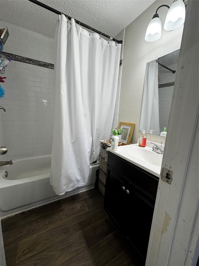 full bathroom with a textured ceiling, a textured wall, wood finished floors, vanity, and shower / tub combo with curtain