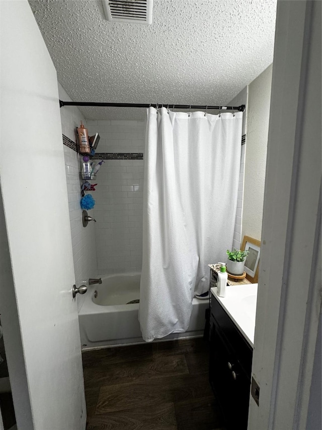 bathroom with visible vents, shower / bathtub combination with curtain, a textured ceiling, vanity, and wood finished floors