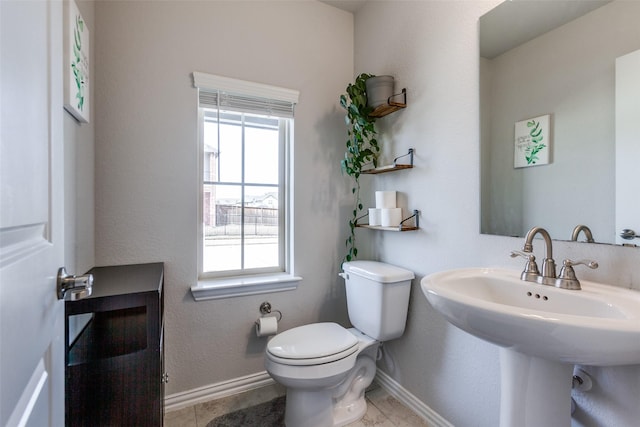 bathroom with toilet, baseboards, and a sink