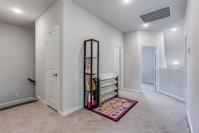 hall with an upstairs landing, visible vents, baseboards, and carpet floors