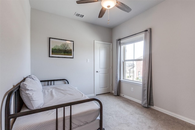 bedroom featuring visible vents, light colored carpet, baseboards, and ceiling fan