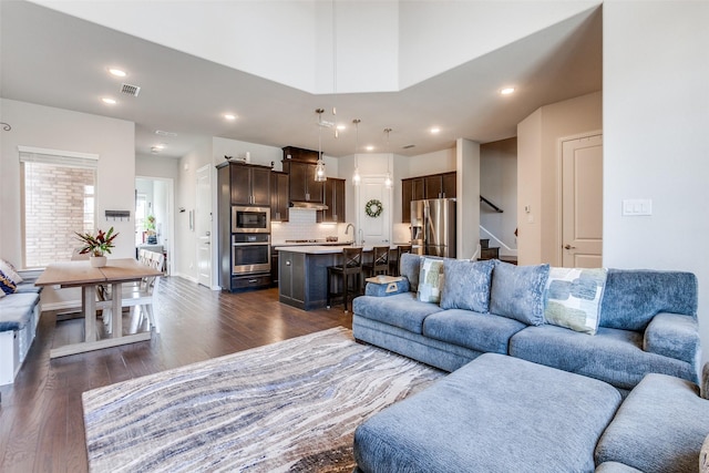 living room featuring dark wood-style floors, stairway, recessed lighting, and visible vents