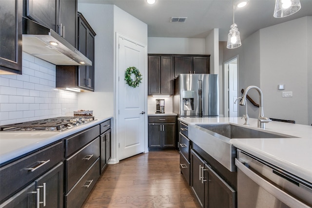 kitchen featuring visible vents, under cabinet range hood, light countertops, dark wood-style floors, and stainless steel appliances