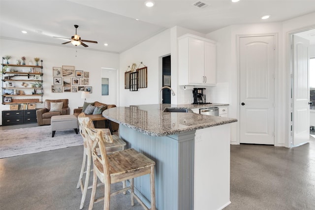 kitchen with light stone counters, recessed lighting, white cabinetry, dishwasher, and a kitchen breakfast bar