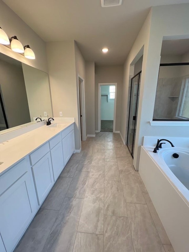 bathroom with a garden tub, double vanity, visible vents, a stall shower, and a sink