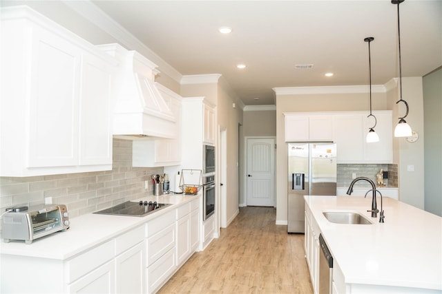 kitchen featuring a toaster, visible vents, custom range hood, appliances with stainless steel finishes, and a sink