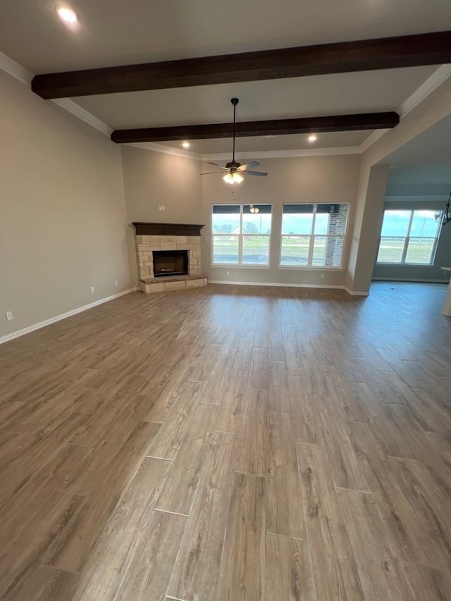 unfurnished living room featuring a wealth of natural light, a stone fireplace, and wood finished floors