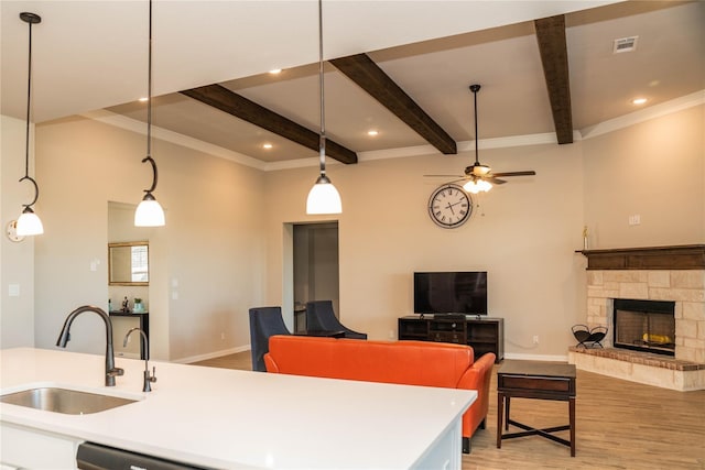 kitchen with a stone fireplace, a sink, visible vents, light wood-style floors, and open floor plan