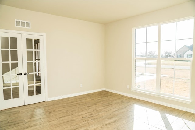 spare room featuring french doors, wood finished floors, visible vents, and baseboards