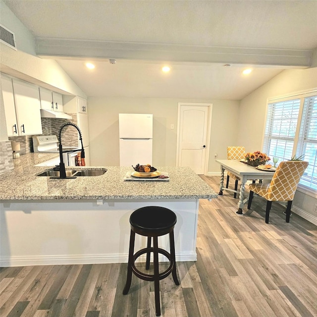 kitchen with lofted ceiling with beams, a peninsula, a sink, and freestanding refrigerator