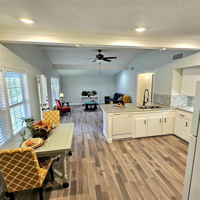 kitchen with visible vents, lofted ceiling with beams, a sink, white appliances, and a peninsula