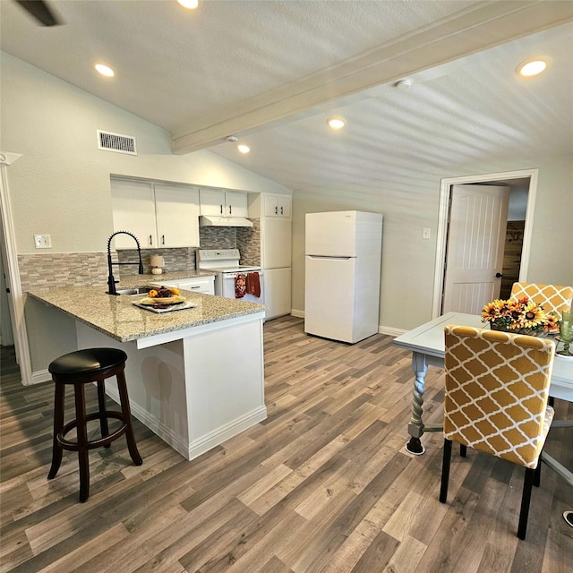 kitchen with vaulted ceiling with beams, a peninsula, white appliances, a sink, and visible vents