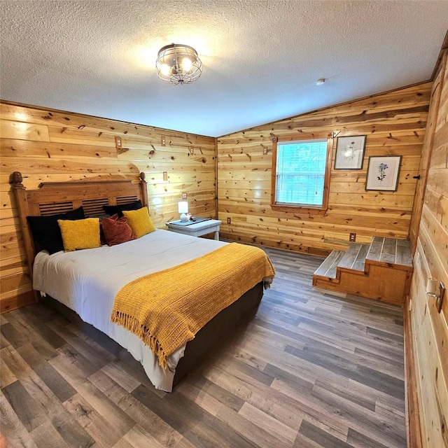 bedroom with wood walls, a textured ceiling, and wood finished floors