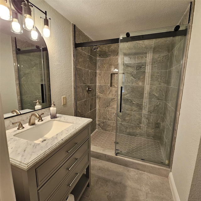 bathroom featuring a stall shower, vanity, a textured ceiling, and a textured wall